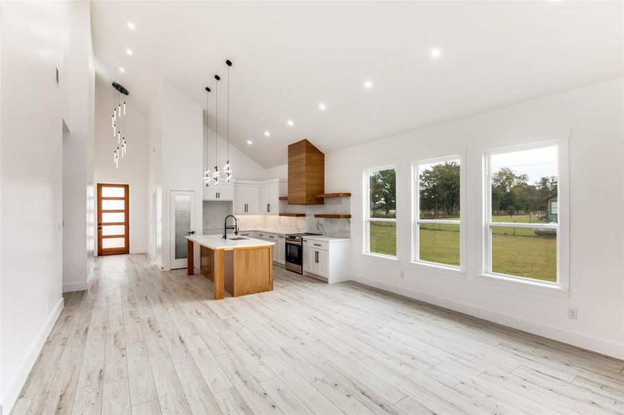 Kitchen featuring open shelves, white cabinetry, backsplash, high vaulted ceiling, and decorative light fixtures Kitchen featuring open shelves, white cabinetry, backsplash, high vaulted ceiling, and decorative light fixtures