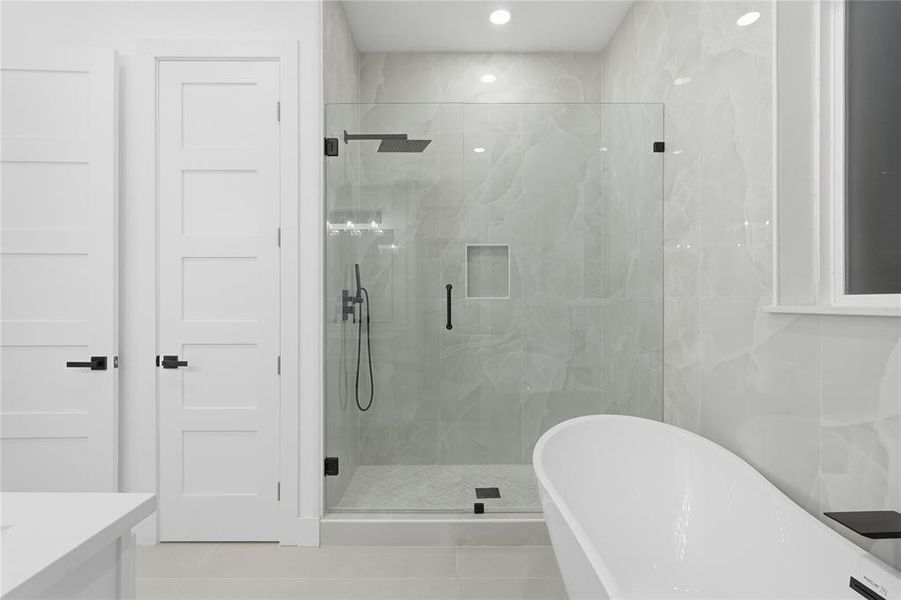 Bathroom with a freestanding bath, a marble finish shower, vanity, and light tile patterned floors