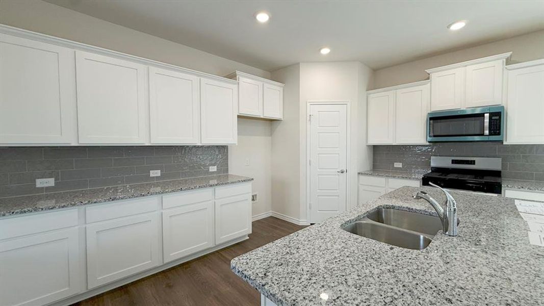 Kitchen with white cabinetry, light stone counters, appliances with stainless steel finishes, and recessed lighting Kitchen with white cabinetry, light stone counters, appliances with stainless steel finishes, and recessed lighting