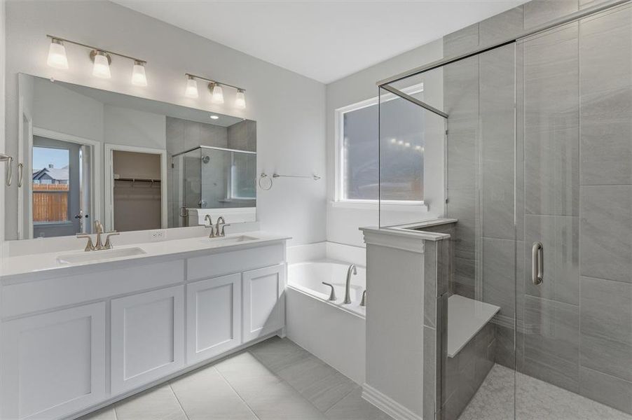 Full bathroom featuring a stall shower, a spacious closet, a bath, and healthy amount of natural light