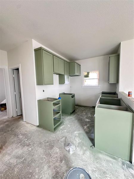 Kitchen featuring green cabinetry and a textured ceiling