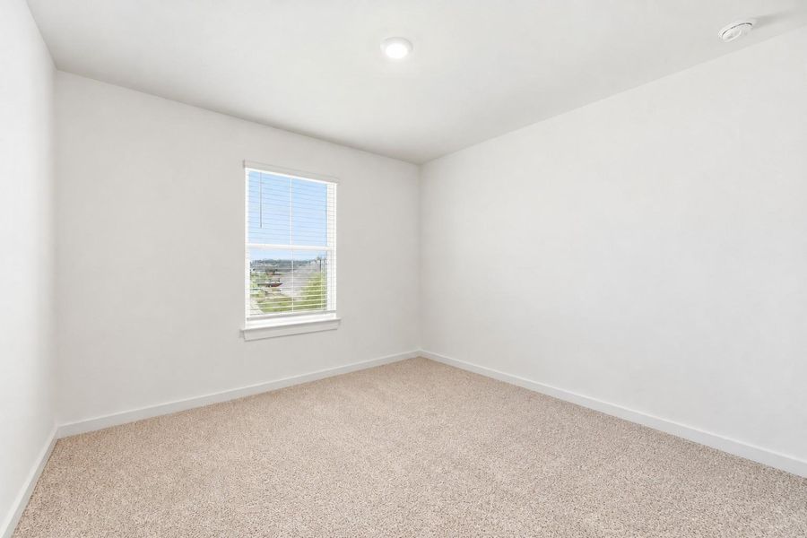 Second upstairs bedroom with carpet, a front yard-facing window and a walk-in closet.