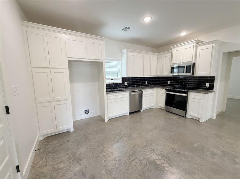 Kitchen featuring backsplash, stainless steel appliances, white cabinets, concrete flooring, and recessed lighting Kitchen featuring backsplash, stainless steel appliances, white cabinets, concrete flooring, and recessed lighting