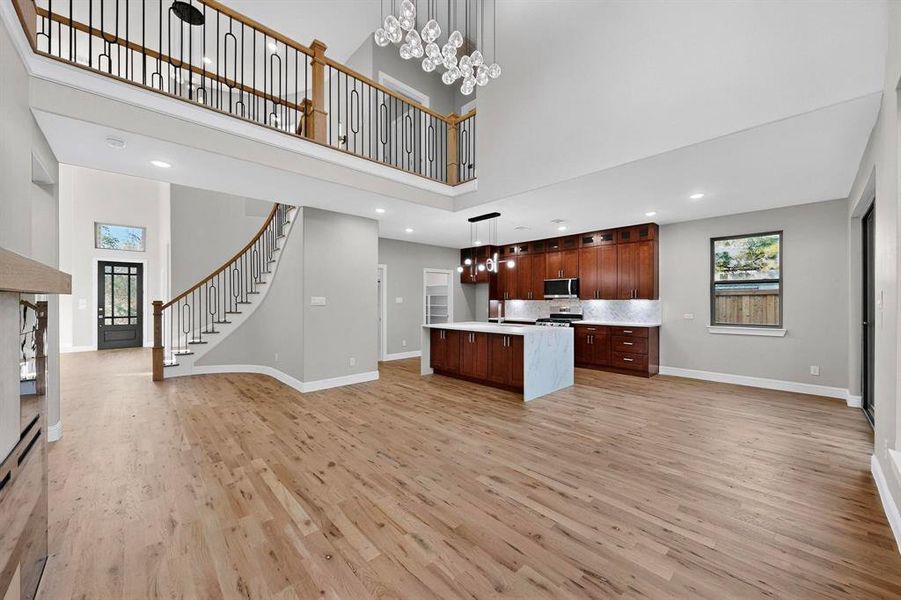 Kitchen with open floor plan, a chandelier, hanging light fixtures, recessed lighting, and a high ceiling