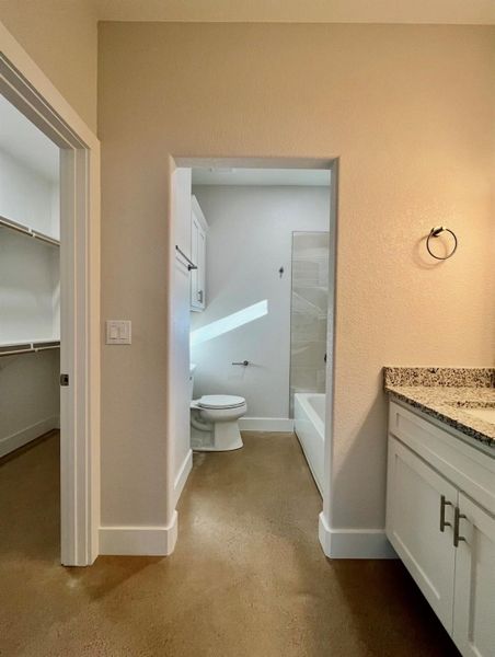 Full bath featuring vanity, a walk in closet, finished concrete floors, and shower / bathtub combination