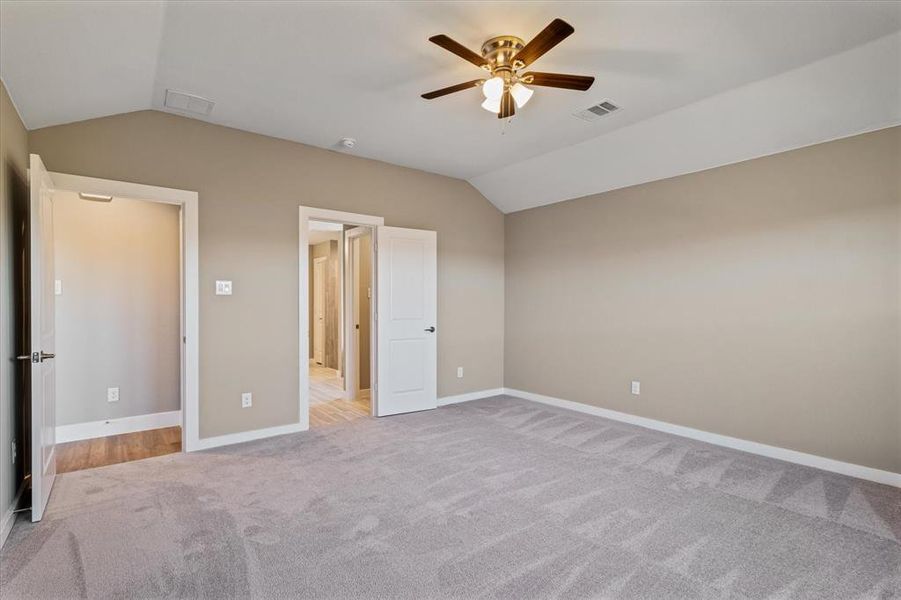 Master bedroom featuring light colored carpet, vaulted ceiling, and ceiling fan