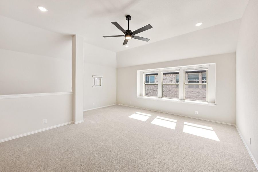 Empty bedroom with vaulted ceiling, ceiling fan, carpet flooring, and large windows Empty bedroom with vaulted ceiling, ceiling fan, carpet flooring, and large windows