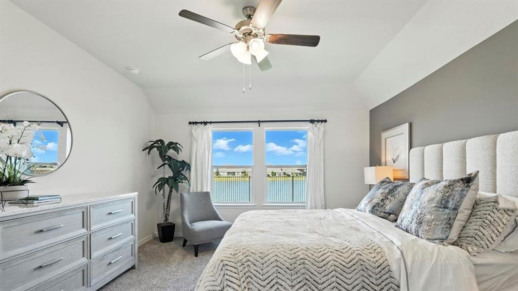 Bedroom with light colored carpet, a ceiling fan, vaulted ceiling, and a water view