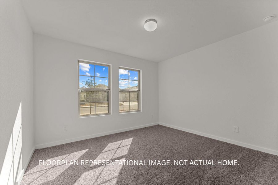 A well-lit bedroom features plush carpeting and two clear windows, perfect for natural illumination.