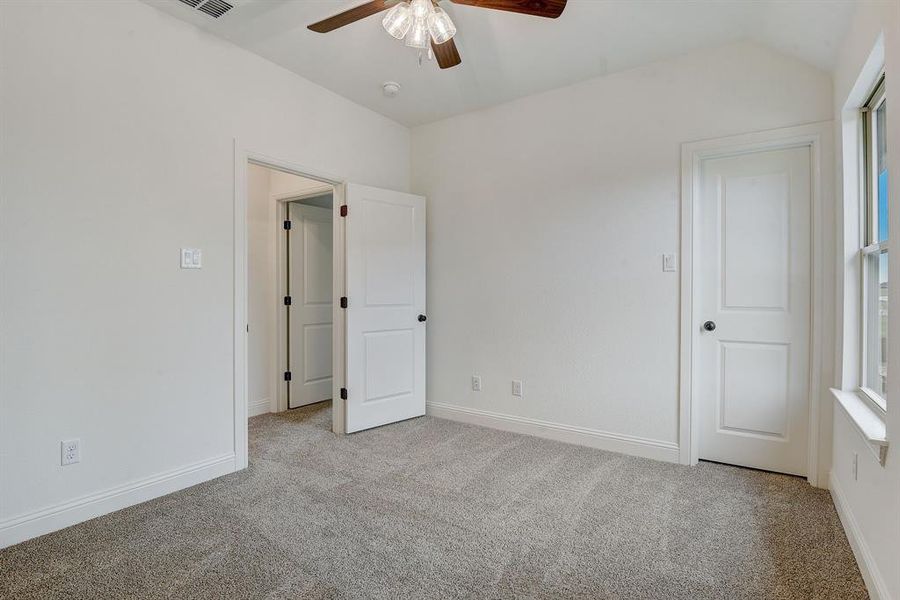 Unfurnished room featuring ceiling fan, carpet flooring, and lofted ceiling