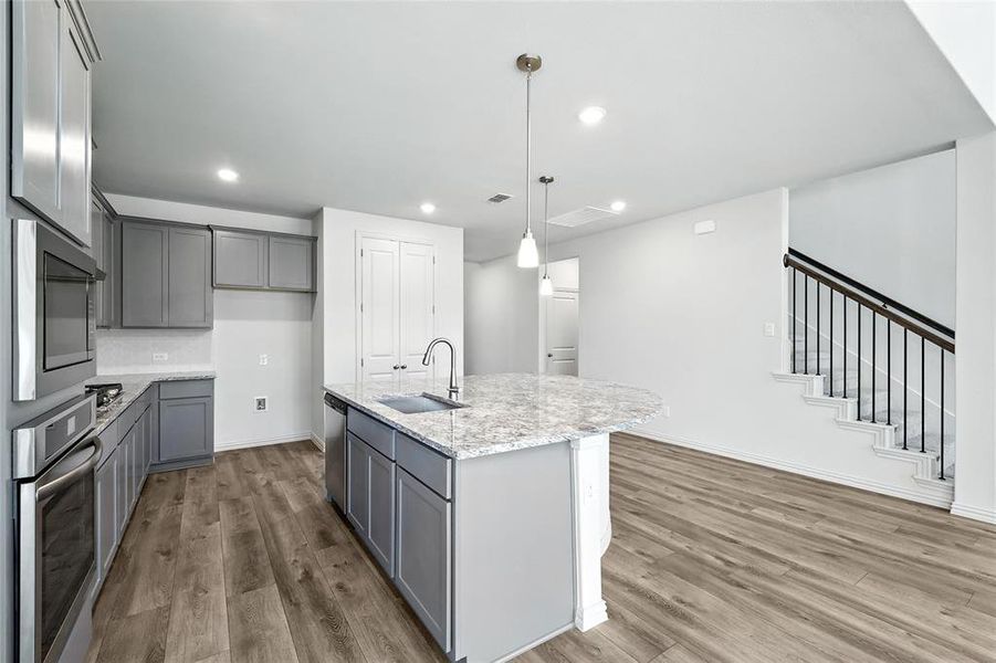 Kitchen featuring appliances with stainless steel finishes, gray cabinets, wood finished floors, light stone countertops, and recessed lighting Kitchen featuring appliances with stainless steel finishes, gray cabinets, wood finished floors, light stone countertops, and recessed lighting
