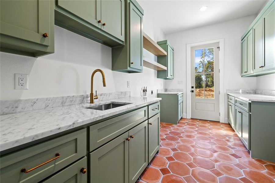 Kitchen with green cabinets, light stone countertops, and light tile patterned floors