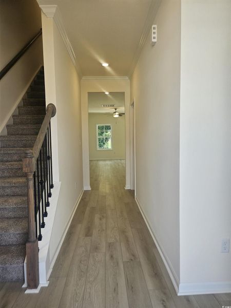 Hall featuring ornamental molding, light wood-style floors, and stairway