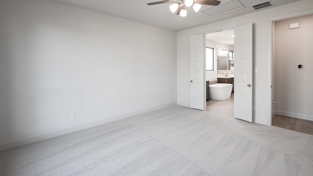 Unfurnished bedroom featuring light carpet, ceiling fan, ensuite bathroom, and attic access Unfurnished bedroom featuring light carpet, ceiling fan, ensuite bathroom, and attic access
