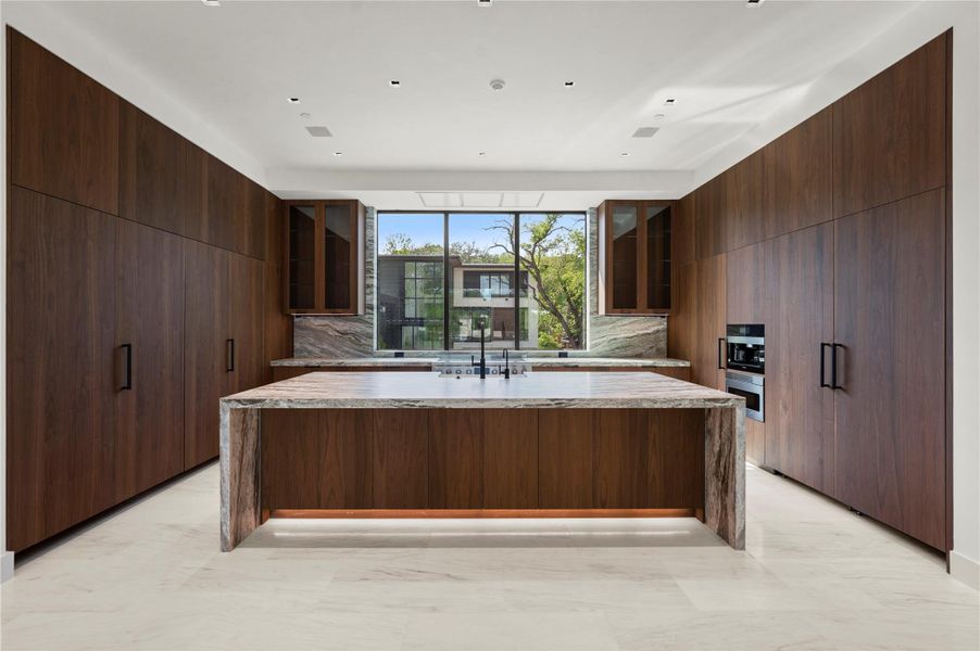 Kitchen featuring a kitchen island with sink, light stone counters, and modern cabinets