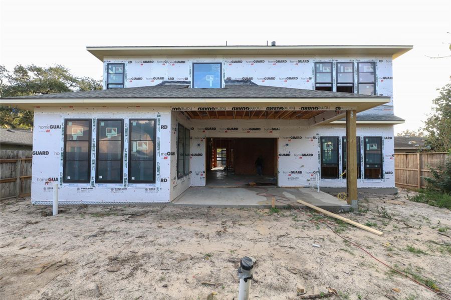 *Construction Progress Photo taken 11/20/25* Rear view of the Home offers over-sized covered patio w/ fully loaded Outdoor Kitchen. Back yard is large enough to install a pool. *Home does not include Pool*.