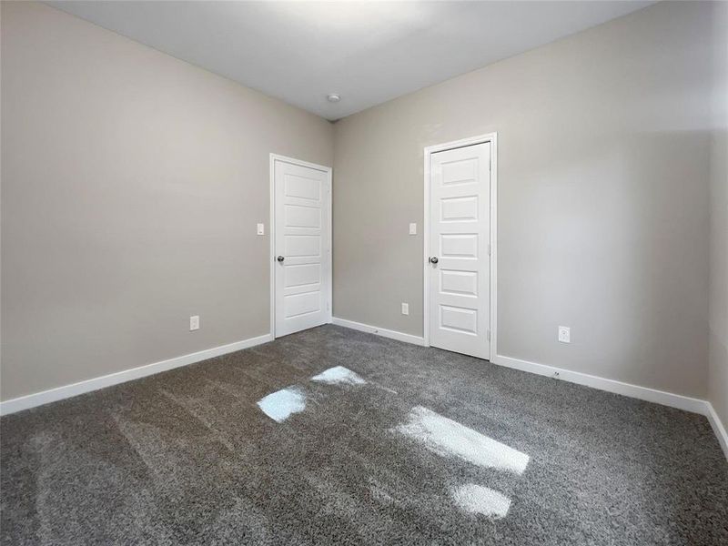 Empty room with dark colored carpet and baseboards