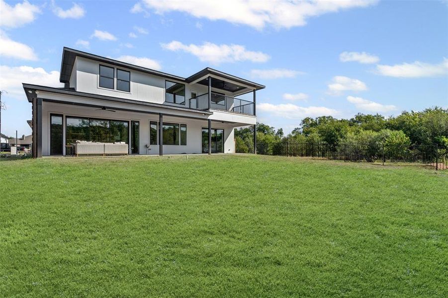 Back of property with ceiling fan, a patio area, a balcony, and an outdoor living space
