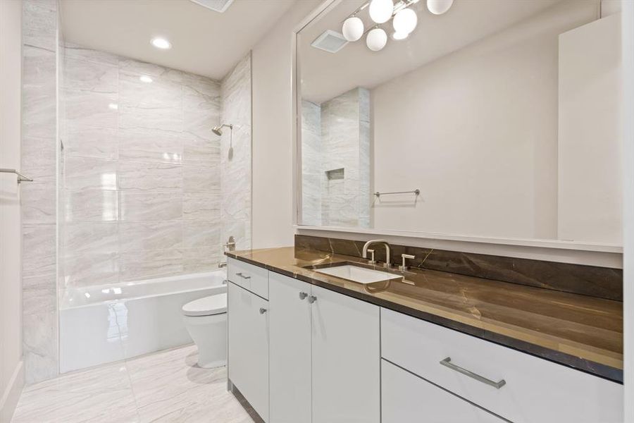 Full bathroom featuring vanity, marble look tiles, bathtub / shower combination, and recessed lighting Full bathroom featuring vanity, marble look tiles, bathtub / shower combination, and recessed lighting