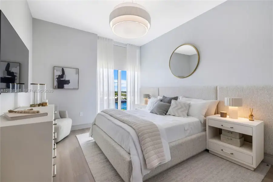 Bedroom featuring wood-finish flooring, floor-to-ceiling windows, a textured fabric headboard wall panel, and a contemporary tiered drum pendant light Bedroom featuring wood-finish flooring, floor-to-ceiling windows, a textured fabric headboard wall panel, and a contemporary tiered drum pendant light