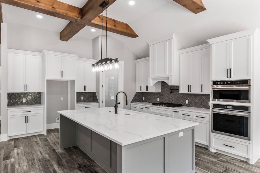 Stunning gourmet kitchen with exposed wooden beams, and an expansive quartz island. Elegant cabinetry and sleek stainless-steel appliances complete the sophisticated look.