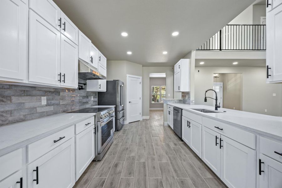 Kitchen featuring tasteful backsplash, white cabinets, a sink, under cabinet range hood, and stainless steel appliances Kitchen featuring tasteful backsplash, white cabinets, a sink, under cabinet range hood, and stainless steel appliances