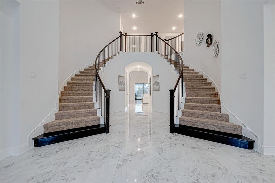 Grand Entryway: Step into luxury with a curved double staircase, a soaring rotunda ceiling, and marbled tile floors throughout the main areas.