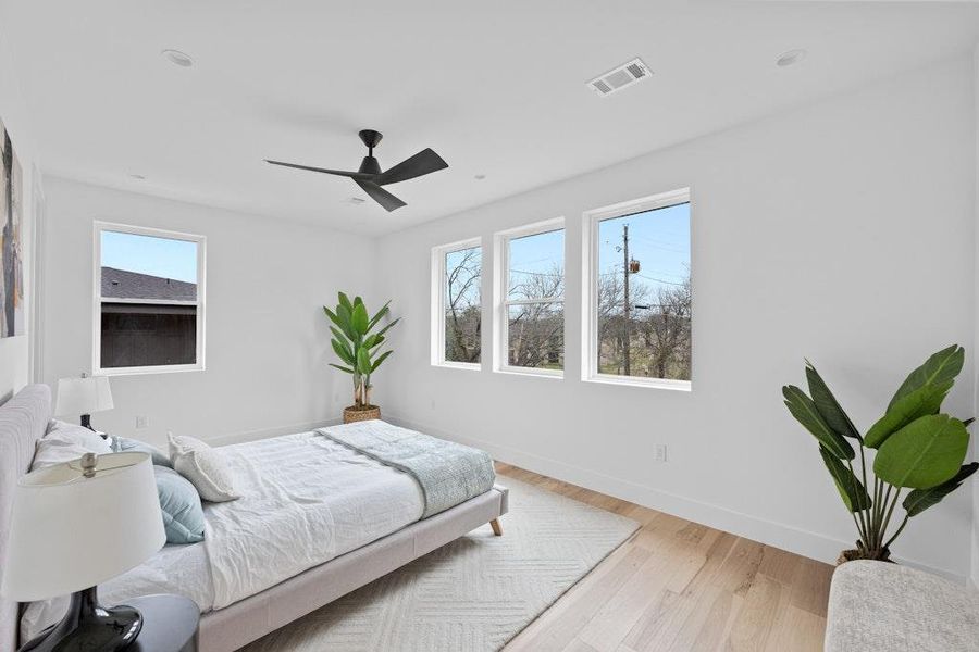 Bedroom with light wood-type flooring, multiple windows, and ceiling fan