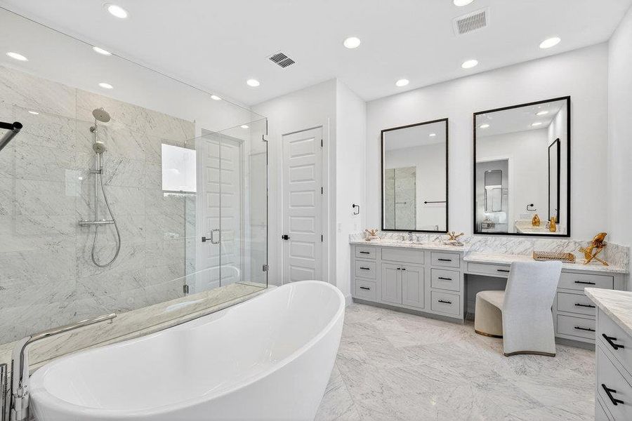 Bathroom with vanity, a freestanding tub, a marble finish shower, light marble finish floors, and recessed lighting