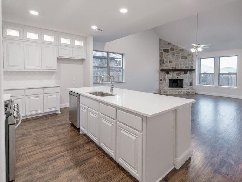 Kitchen with appliances with stainless steel finishes, an island with sink, white cabinets, dark hardwood / wood-style flooring, and decorative backsplash