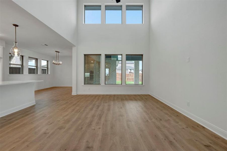 Unfurnished living room with light wood-style floors, a high ceiling, and a chandelier