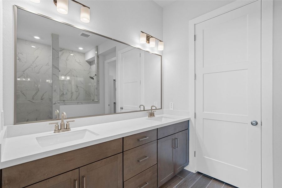 Retreat to a private, spa-like primary bathroom designed for relaxation and convenience. A generous double vanity with modern cabinetry offers ample space for two people. The connecting walk-in closet makes getting ready convenient. Retreat to a private, spa-like primary bathroom designed for relaxation and convenience. A generous double vanity with modern cabinetry offers ample space for two people. The connecting walk-in closet makes getting ready convenient.