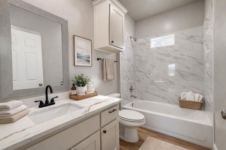 Bathroom featuring bathing tub / shower combination, vanity, and light wood-style flooring Bathroom featuring bathing tub / shower combination, vanity, and light wood-style flooring