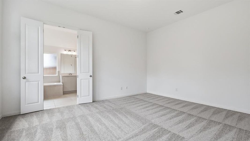 Spacious room with light gray carpet featuring a geometric pattern Spacious room with light gray carpet featuring a geometric pattern