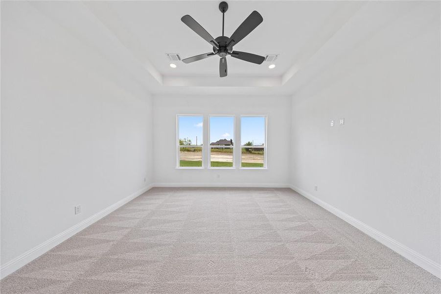 Spare room featuring light carpet, ceiling fan, a raised ceiling, and recessed lighting