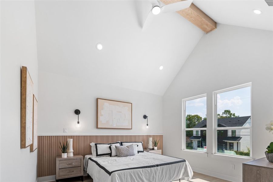 vaulted ceilings with a dramatic wood beam and a fluted wood accent wall that mirrors the style of the secondary living area. This striking mix of textures and architectural detail creates a serene, luxurious retreat