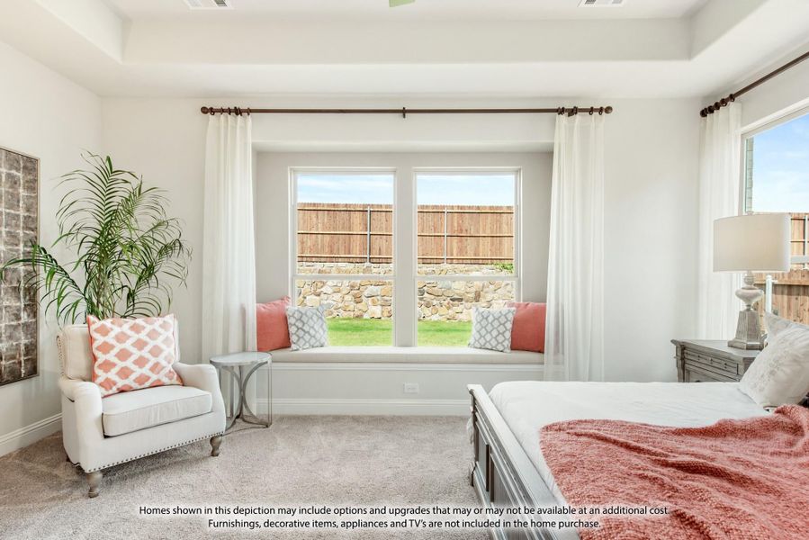 Bedroom with tray ceiling, built-in window seat, carpet flooring, and large windows overlooking a backyard Bedroom with tray ceiling, built-in window seat, carpet flooring, and large windows overlooking a backyard