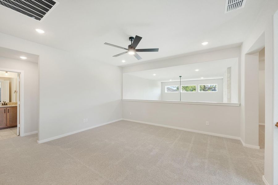 Spacious bedroom with carpet flooring, ceiling fan, and an attached bathroom visible through doorway. Spacious bedroom with carpet flooring, ceiling fan, and an attached bathroom visible through doorway.