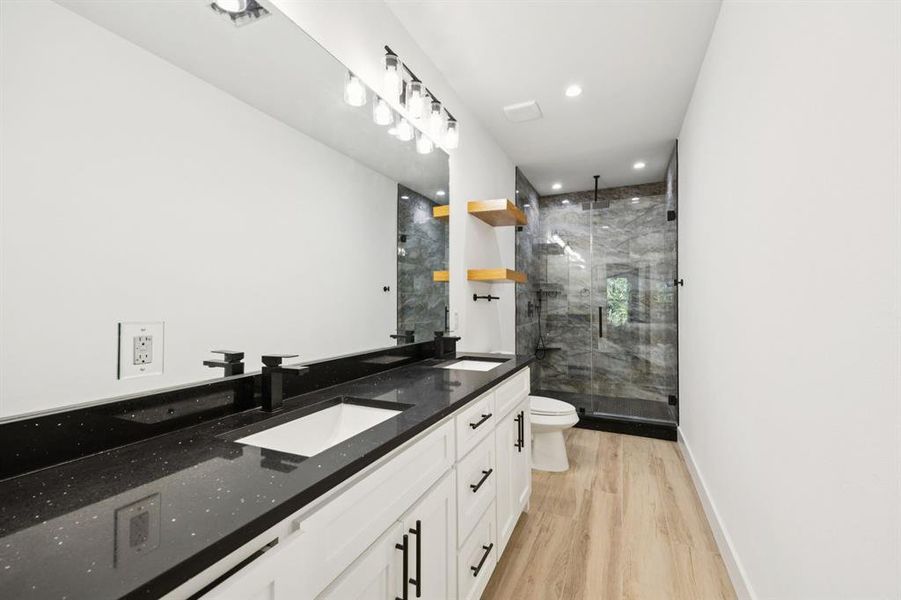 Full bathroom with double vanity, light wood-style floors, a stall shower, and recessed lighting