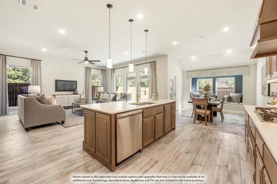 Open-concept kitchen with wood cabinet island, white countertops, and light hardwood floors flowing into living and dining areas