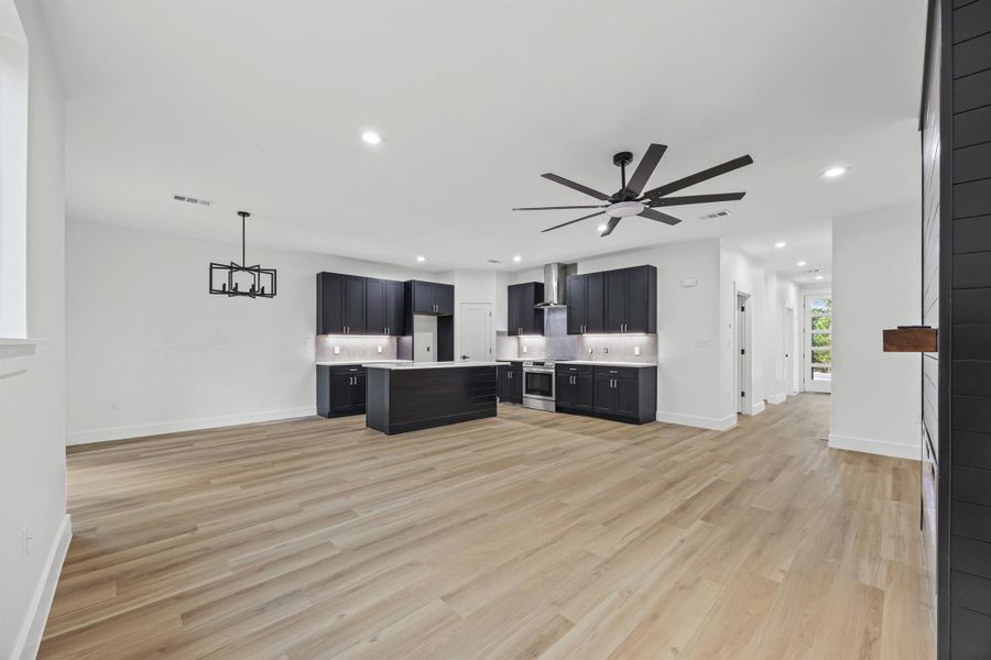 Kitchen featuring dark cabinets, light countertops, backsplash, light wood-type flooring, and recessed lighting