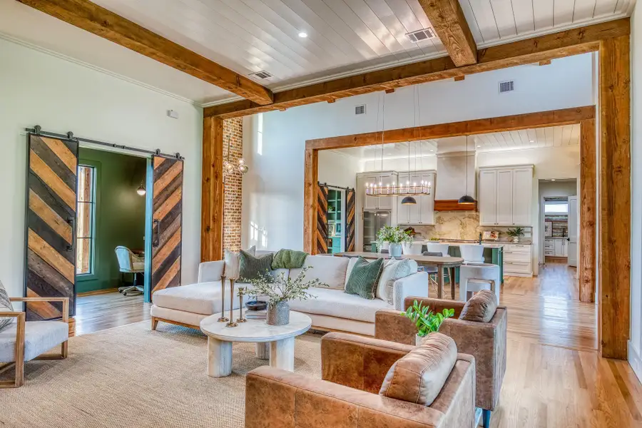 Living room featuring beam ceiling, light wood-style floors, a barn door, a chandelier, and recessed lighting Living room featuring beam ceiling, light wood-style floors, a barn door, a chandelier, and recessed lighting