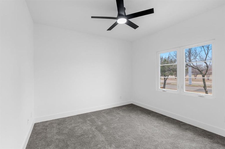 Carpeted spare room featuring ceiling fan