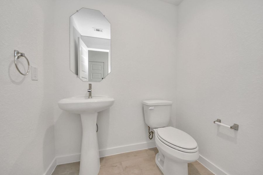 This half bathroom features a stylish pedestal sink, modern hardware, and bright recessed lighting, creating a sleek and inviting space.
