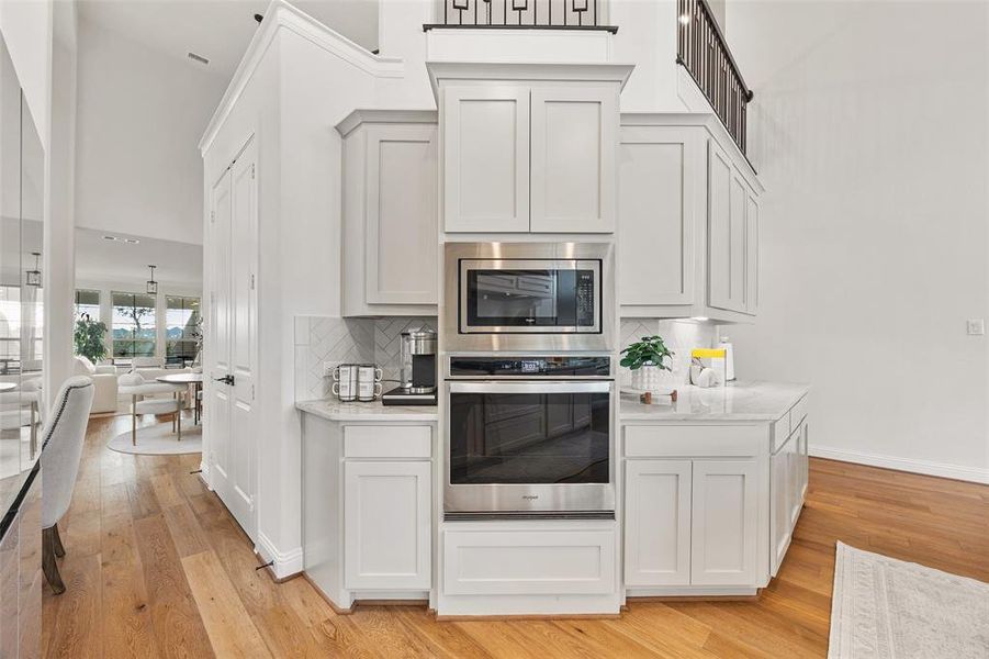 Kitchen featuring light wood-type flooring, light countertops, a towering ceiling, and stainless steel appliances