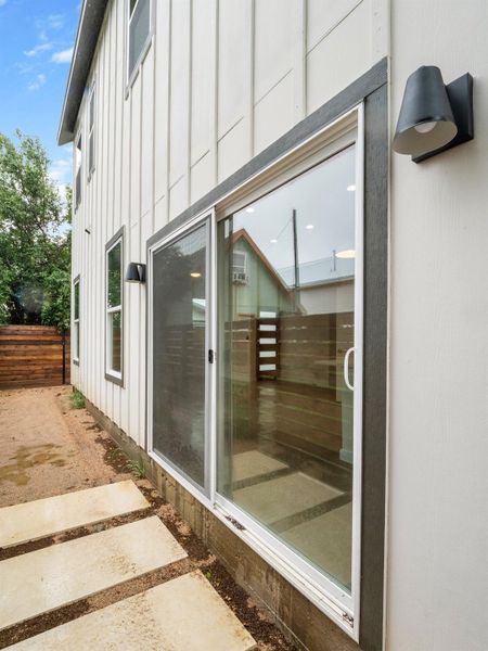 Modern exterior featuring white vertical siding, contemporary sconce lighting, and a large sliding glass door