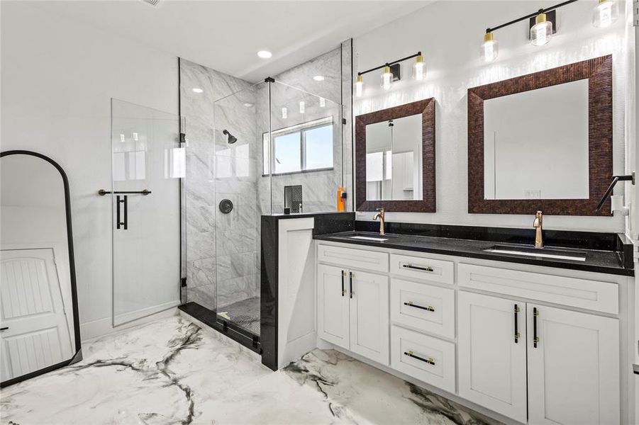 Full bathroom with light marble finish flooring, a marble finish shower, and double vanity Full bathroom with light marble finish flooring, a marble finish shower, and double vanity