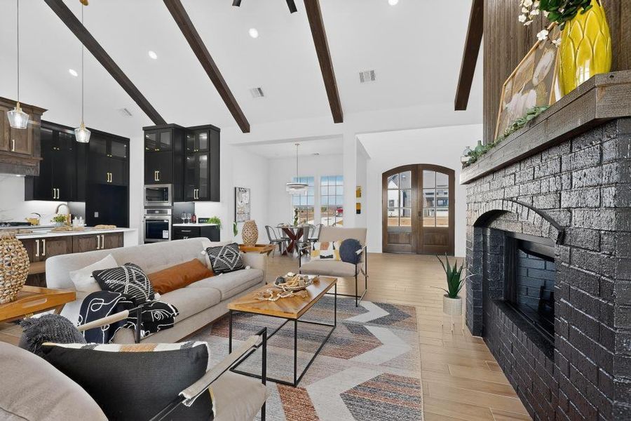Living room with light wood-style flooring, a brick fireplace, french doors, and vaulted ceiling