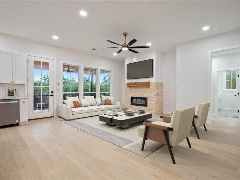 The living area features light-toned flooring and recessed lighting, with a fireplace that has a stone surround and a wooden mantel
