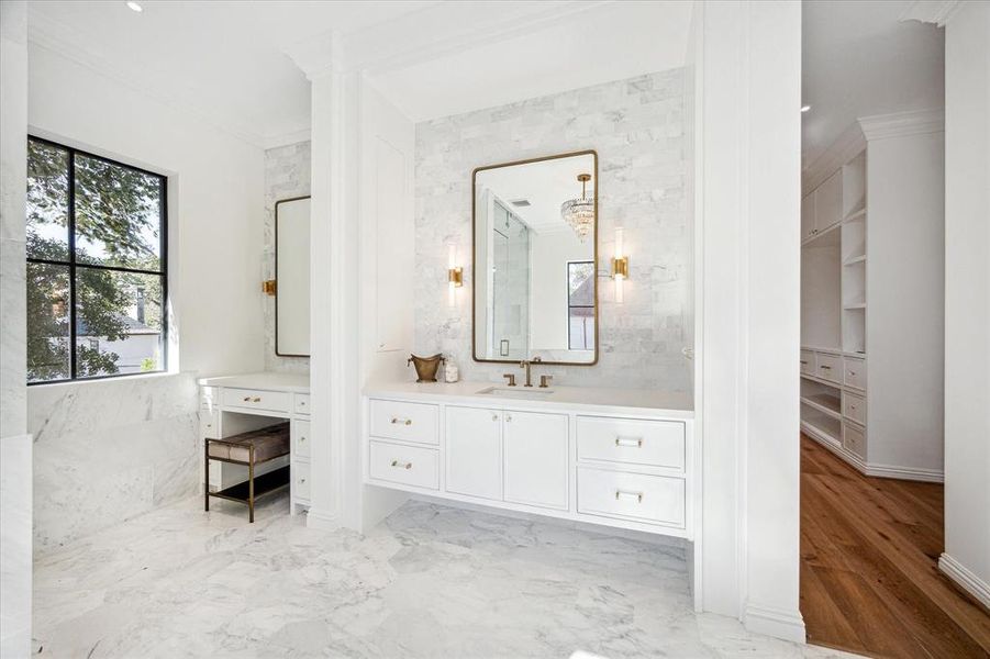 This stunning primary bathroom is elegantly swathed in marble, featuring an exquisite soaking tub that invites relaxation. A spacious walk-in shower and a thoughtfully designed vanity with knee space offer both luxury and practicality, all framed by stunning treetop views.